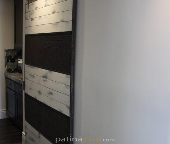 ranch style barn door with wire mesh and white weathered paint