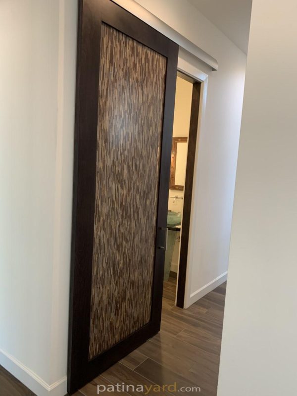 Dark stained alder wood barn door with a woven look 3form resin panel