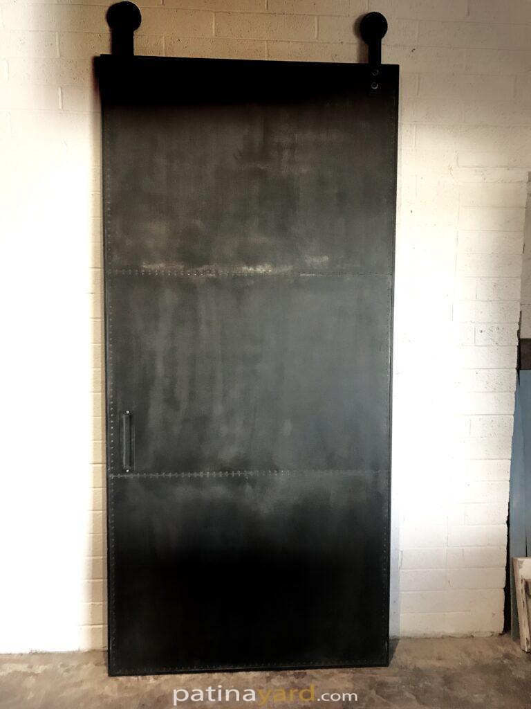 metal steel panel door with rivets and blackened patina