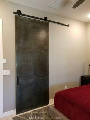 3 Panel Metal Barn Door with Mirrored Back Steel panel barn door with rivets in the seams and patina finish