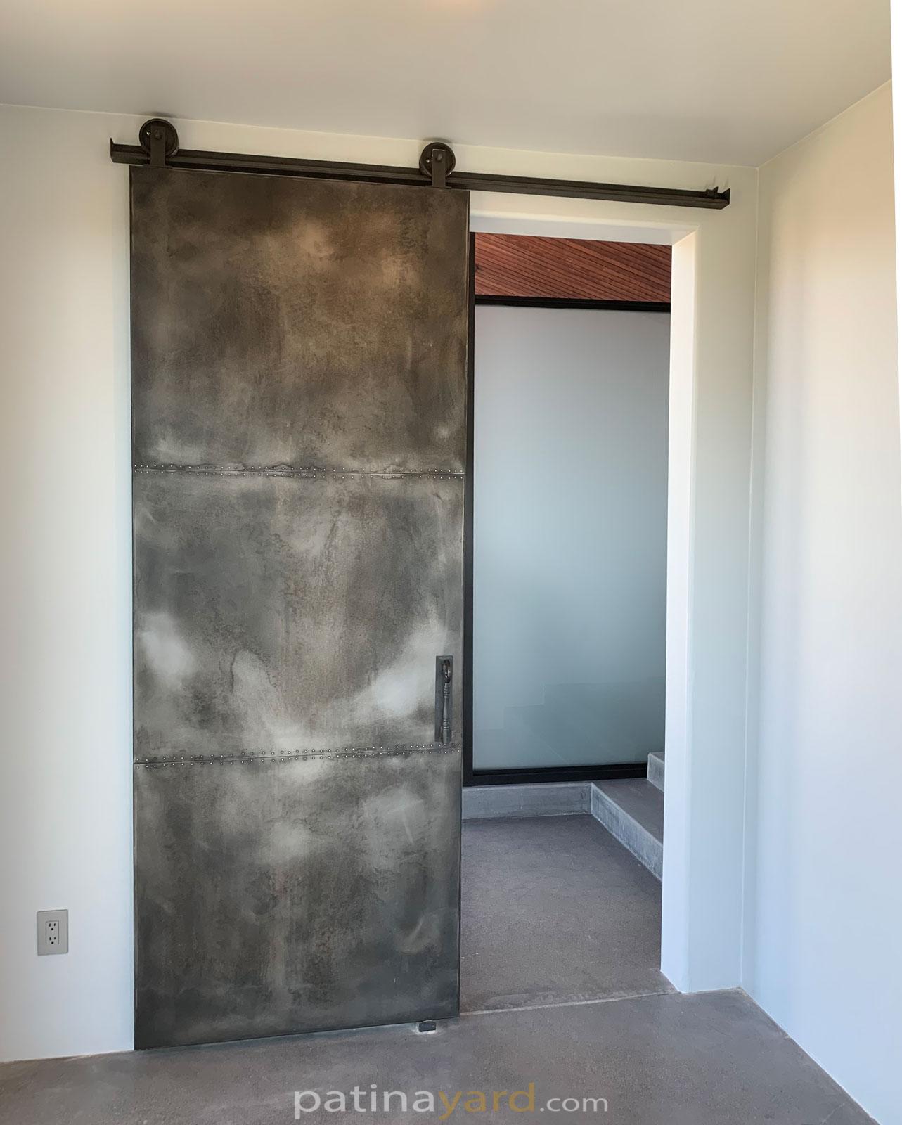 weathered zinc barn door with rivets