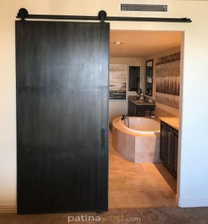 Steel Skinned Barn Door with Small Rivets metal barn door with a patina finish and custom hardware