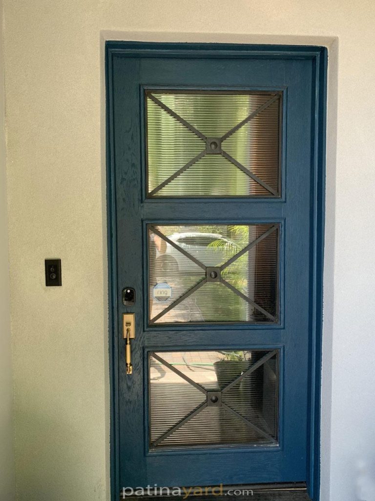 Teal painted white oak front door with reeded glass panels and metal X overlays