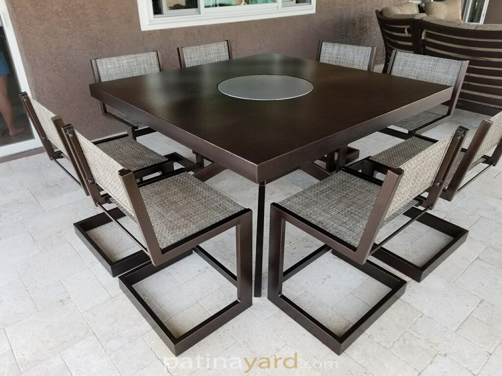 Square dark metal dining table with metal chairs and a center lazy susan