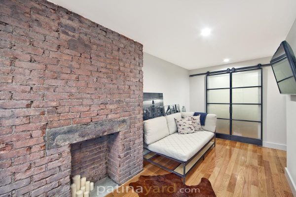 Warehouse style double steel and glass barn doors in a New York loft living room with a brick fireplace