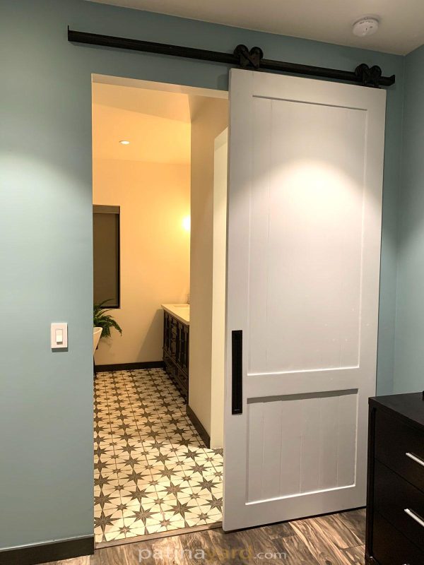 White 2 panel shaker barn door opening to a bathroom with patterned tile