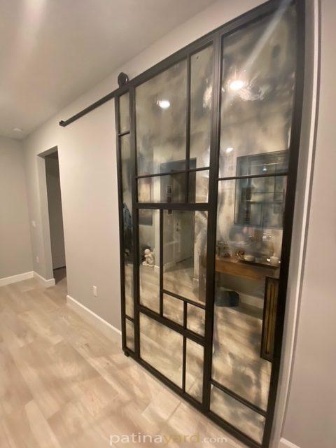 Antique mirror and metal barn door sliding along a hallway wall