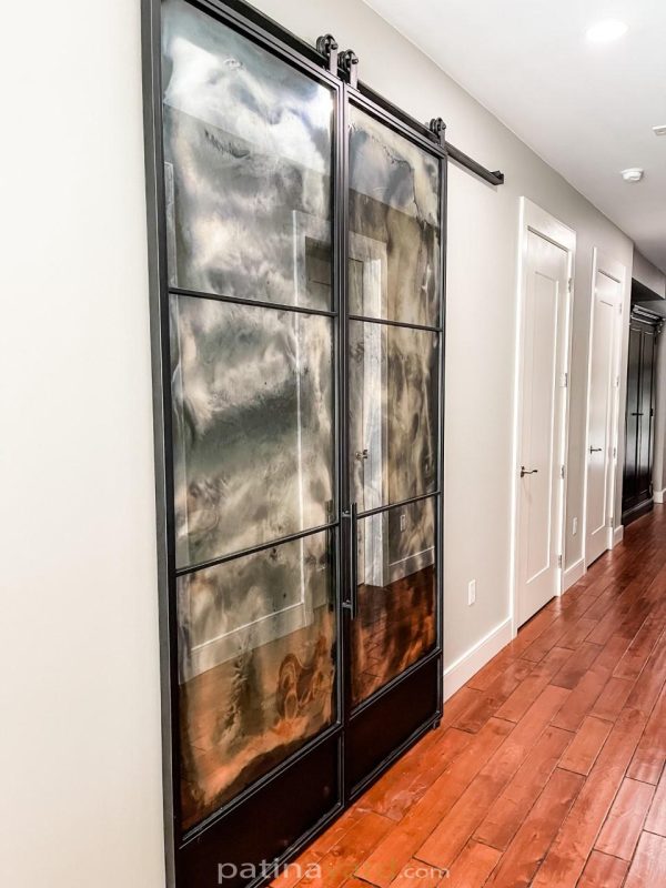 Double antique mirror and metal barn doors in a hallway