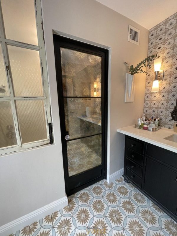 Hinged Antique Mirror Door Hinged antique mirror and metal door at a bathroom entry with patterned tile