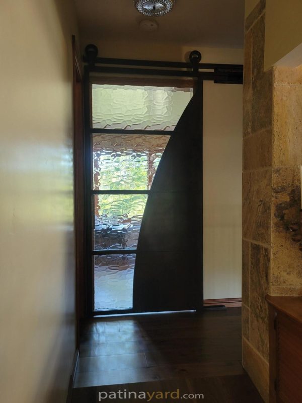 Industrial contemporary steel and specialty glass door with a curved dark metal panel