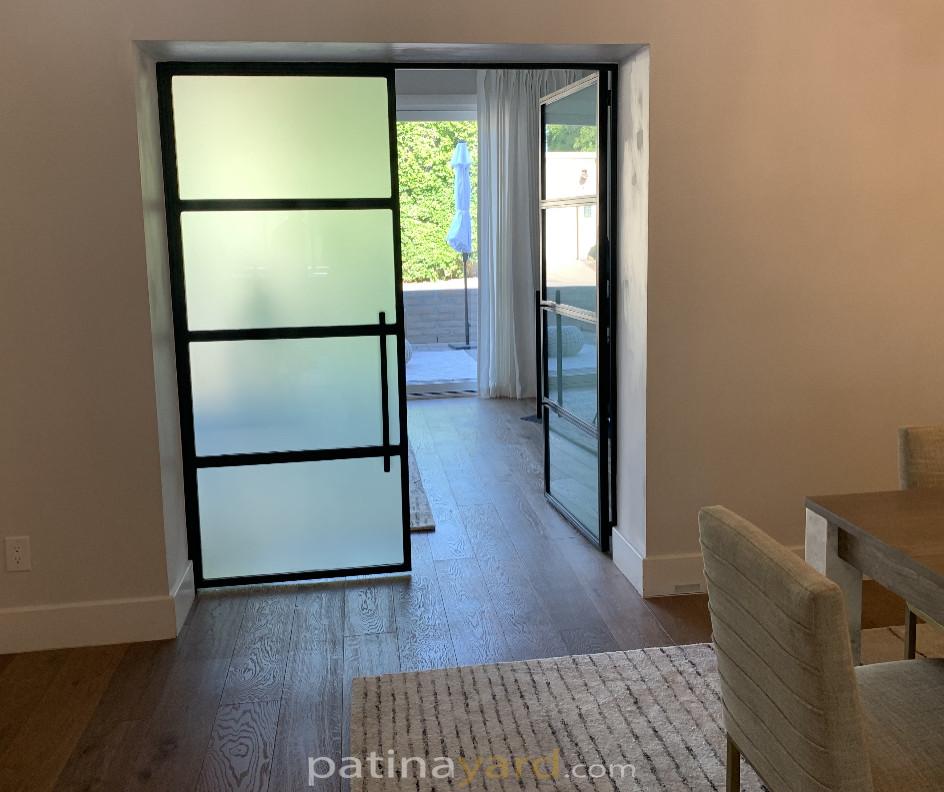 Metal and satin glass hinged doors opening to a dining area