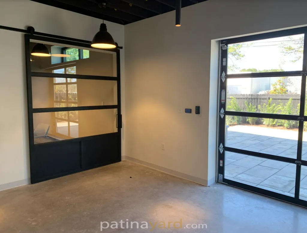 Oversized metal and glass barn door with a black frame in a room with large windows