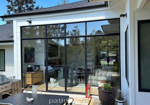 Black metal and glass double doors with sidelights opening to a patio