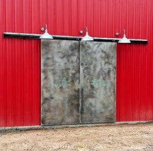 Aluminum doors Aluminum barn doors with a patina finish on a building with red metal siding