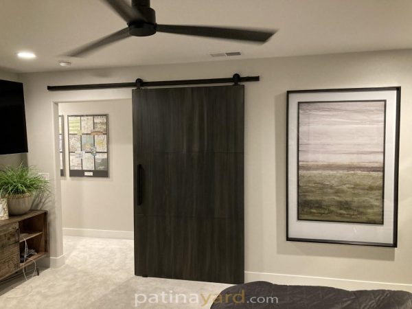 Single dark metal panel barn door in a living room with a ceiling fan