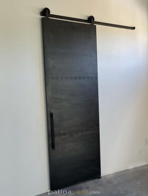 Three panel dark metal barn door with rivets on a black track