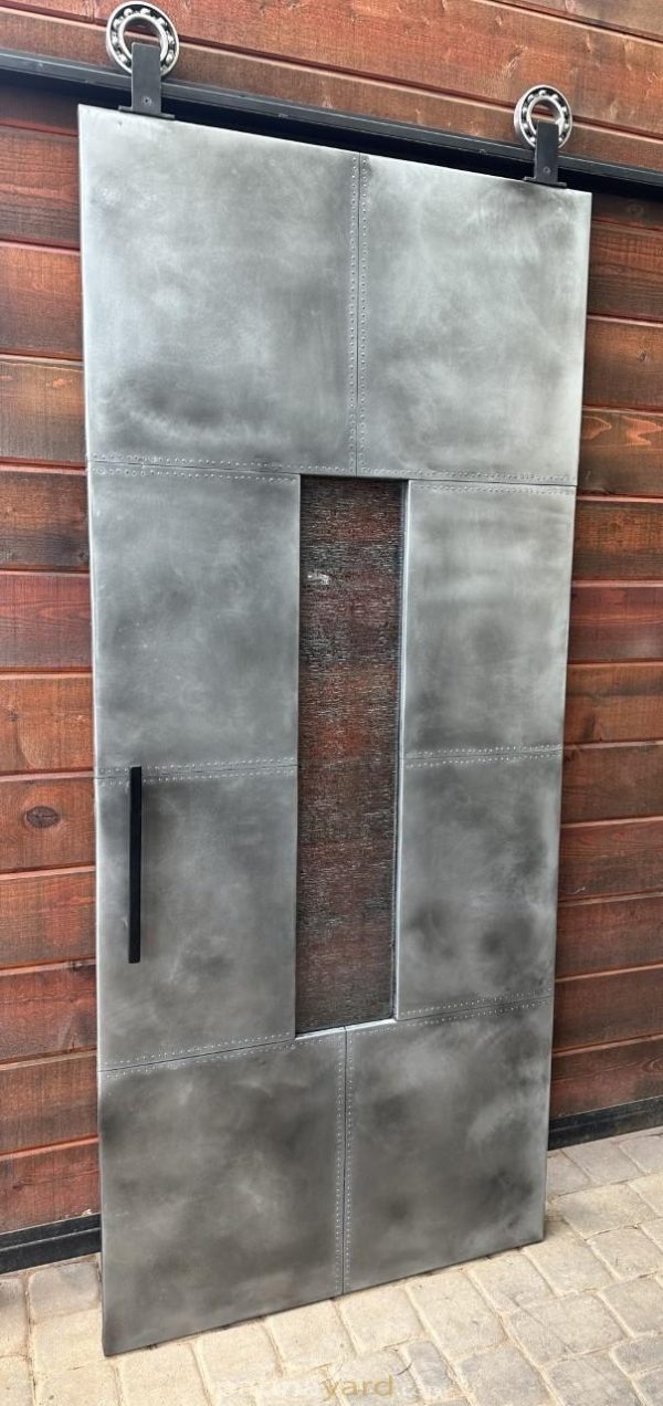 Zinc barn door with a specialty glass inset against a brick wall