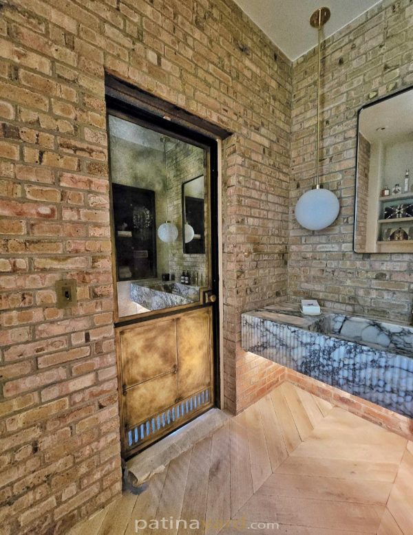 brass antique mirror barn door Brass antique mirror door set into a brick wall