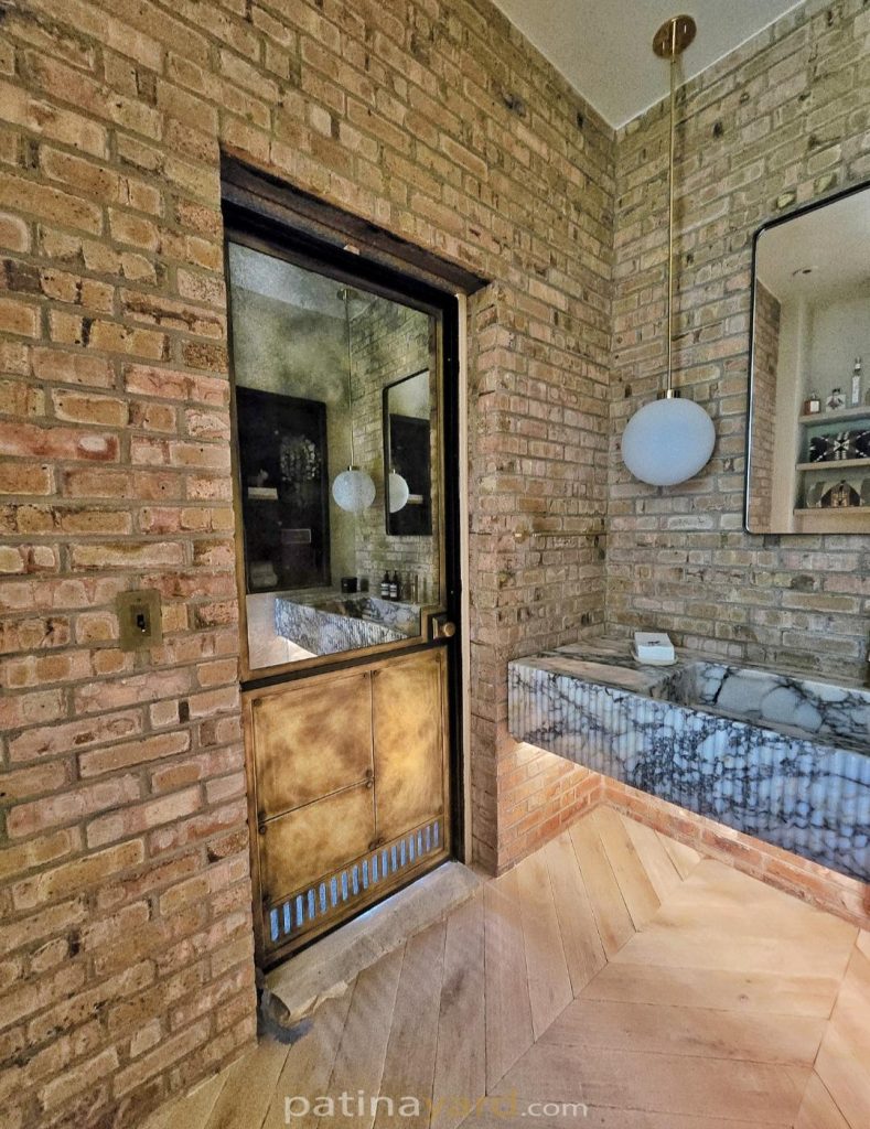Brass antique mirror door set into a brick wall
