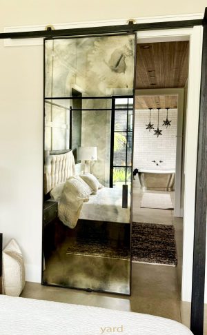 Antique Mirror Barn Door Single panel antique mirror barn door beside a bedroom