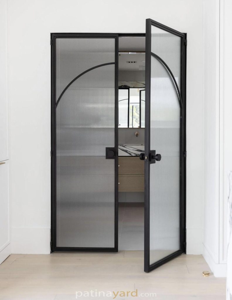 Reeded glass double entry doors to master bath with blackened metal frames