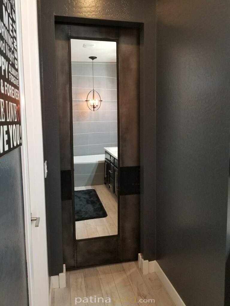 Patina metal panel pocket door with large mirror
