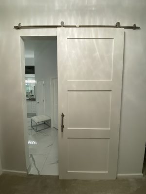3 Panel Painted Shaker Door White 3 panel painted shaker barn door opening to a marble bathroom
