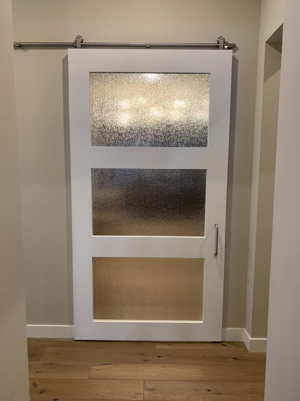 White painted wood barn door with three rain glass panels