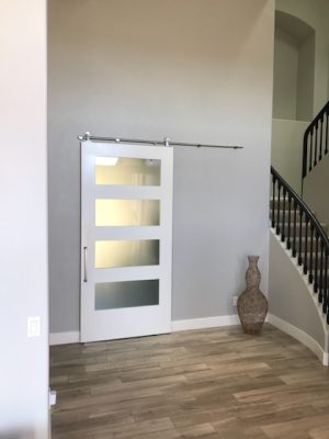 4 Panel Satin Glass and Shaker Style Barn Door White painted shaker barn door with four satin glass panels near a staircase