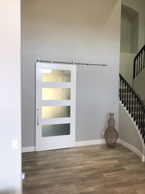 White painted shaker barn door with four satin glass panels near a staircase