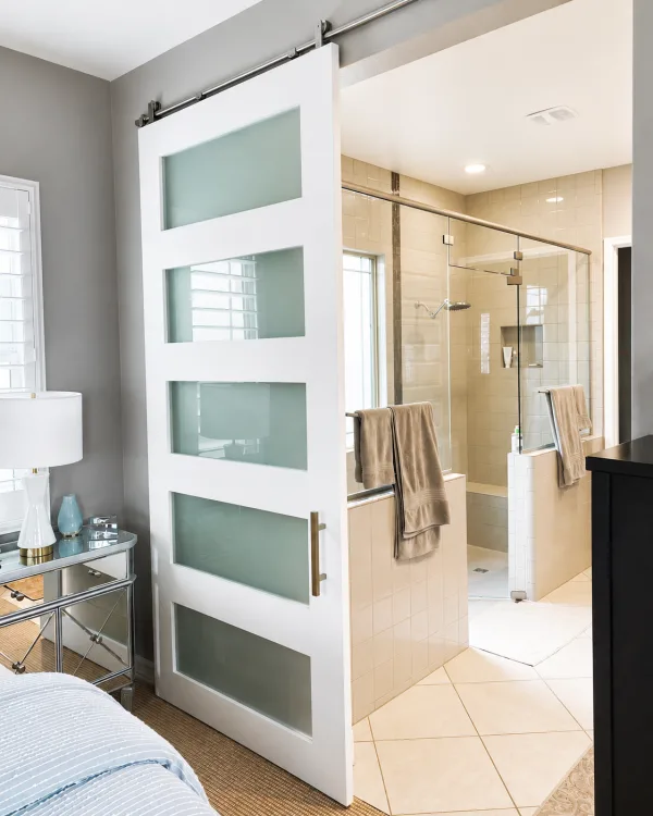 White shaker barn door with five satin glass panels opening to a bathroom