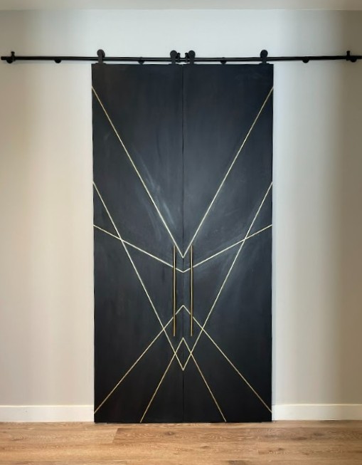 Black stained white oak double barn doors closed showing the diagonal brass inlay pattern