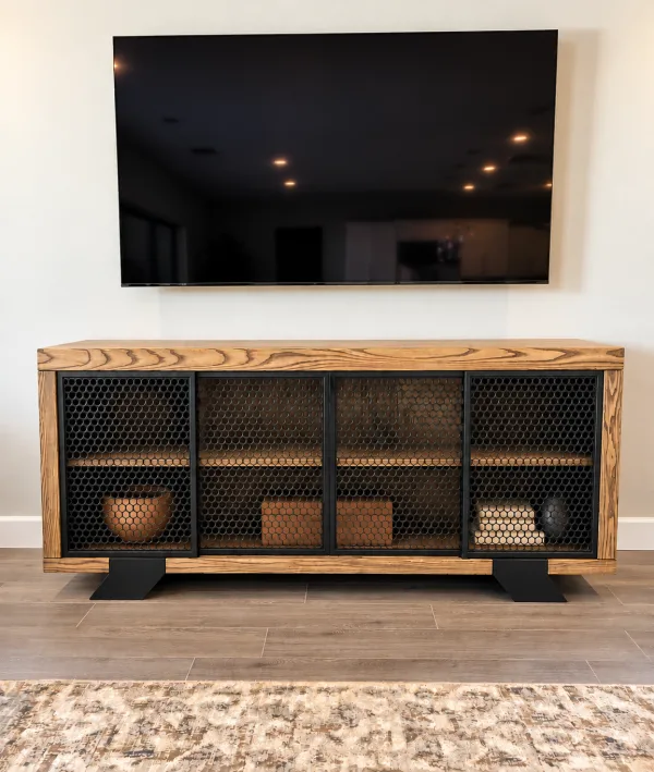 Ash Wood and Metal Credenza Ash wood credenza with perforated black metal sliding doors under a wall mounted TV