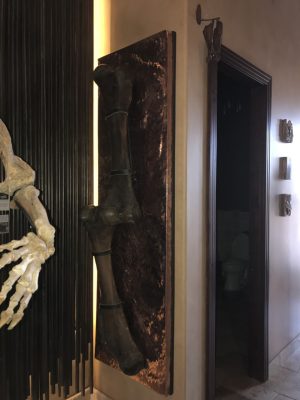 Hammered copper wall art piece displaying a large bone