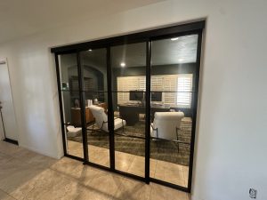 Black metal and glass sliding doors and sidelights on a concealed upper track enclosing a living room