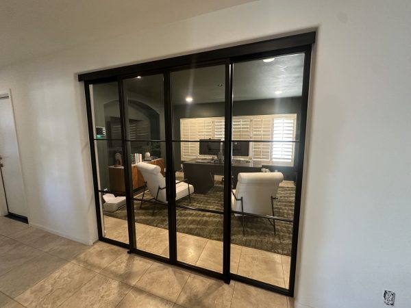 Black metal and glass sliding doors and sidelights on a concealed upper track enclosing a living room