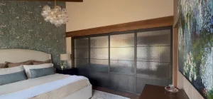 Black metal and specialty glass sliding doors with an upper concealed track in a bedroom