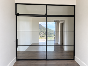 Black steel and glass sliding barn door with fixed panel and transom in Fountain Hills, Arizona