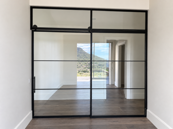 Black steel and glass sliding barn door with fixed panel and transom in Fountain Hills, Arizona