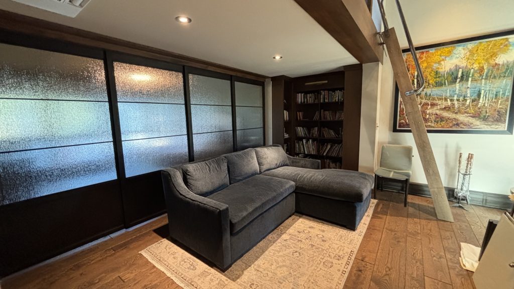 Upper sliding metal and specialty glass doors behind a sofa in a den