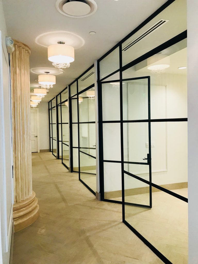 Row of black steel and glass warehouse style doors and sidelights along a spa hallway