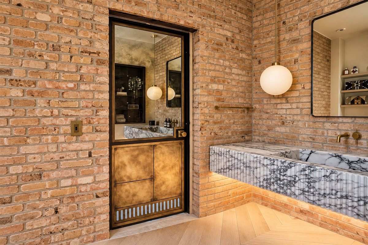 Antique mirror hinged door in a black steel frame in a brick wall bathroom