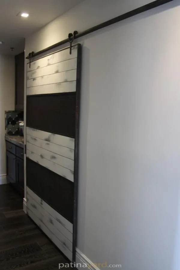 ranch style barn door with wire mesh and white weathered paint
