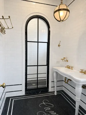 Arched black metal and glass shower door in a master bathroom