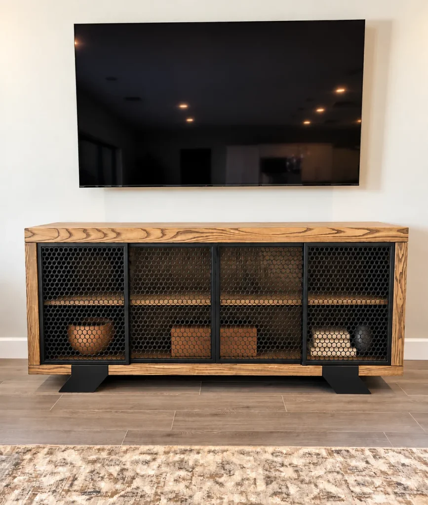 Ash wood credenza with perforated black metal sliding doors under a wall mounted TV