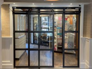 Automatic Open Metal and Glass Barn Doors Automatic opening black metal and glass barn doors in front of a retail display