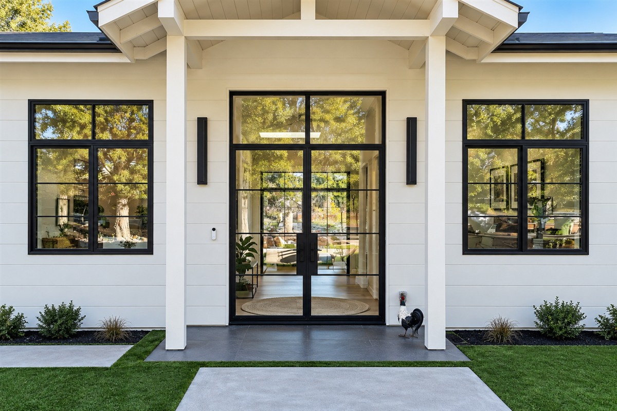 Black metal and glass double entry doors with a transom on a white home