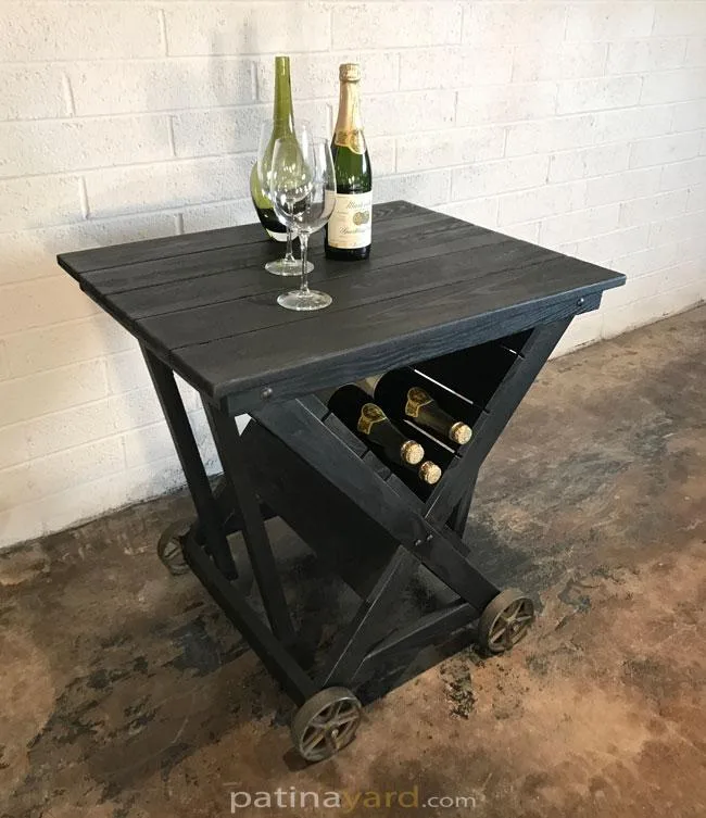 Charred ash wine cart with iron casters and wine bottles in a V shaped rack, with two glasses on top