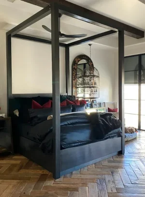 Custom Canopy Metal Bed Frame Black metal four poster canopy bed frame on a herringbone wood floor