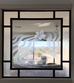 Black metal interior window with etched specialty glass and a frosted glass border